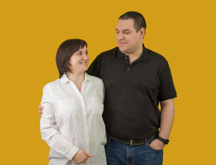 a woman in white and a man in black hug and look at each other on a yellow background