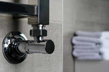 fragment of a chrome steel bathroom towel dryer on the gray anthracite tile wall