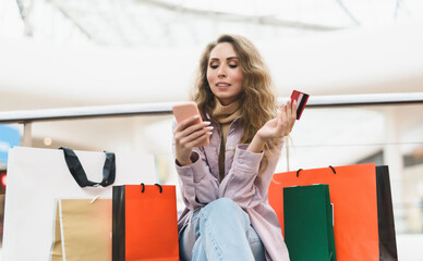 A young woman shopping in an online store pays with a credit card online. Shopaholic concept.