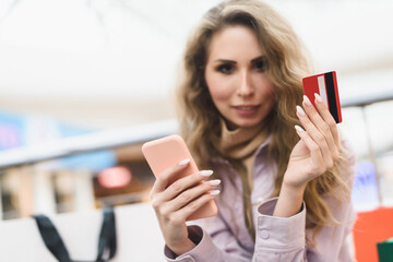 A young woman shopping in an online store pays with a credit card online. Shopaholic concept.