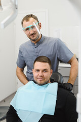 Obraz premium Portrait of a friendly doctor and patient after a successful dental treatment. Demanded dentist. Satisfied customer. Modern dental clinic