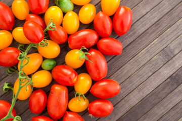 ripe appetizing yellow and red cherry tomatoes with place for inscription on wooden table