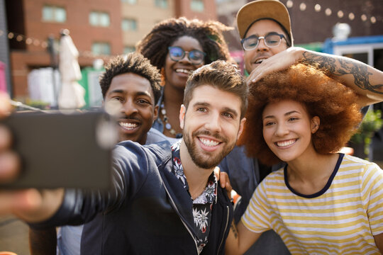 Diverse happy young friends taking selfie with camera phone