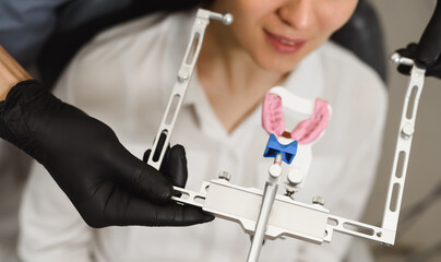 An experienced dentist placing a facial bow for woman patient to examine the bite. Modern technologies in dental treatment