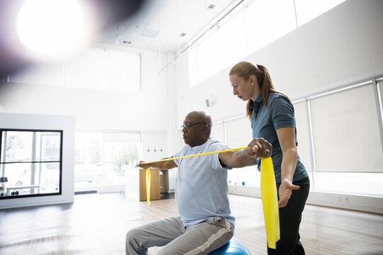 Physiotherapist guiding patient with resistance band stretch in clinic