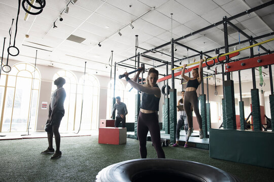 Woman Doing Tire Sledgehammer Exercise In Cross Training Gym