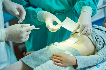 surgeon applies bandage on wound of child's abdomen