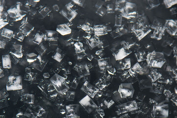 Table salt Isometric, cubic transparent crystal growth from a supersaturated NaCl solution in water.  Examples of crystalline structure. Dark background. View from above.