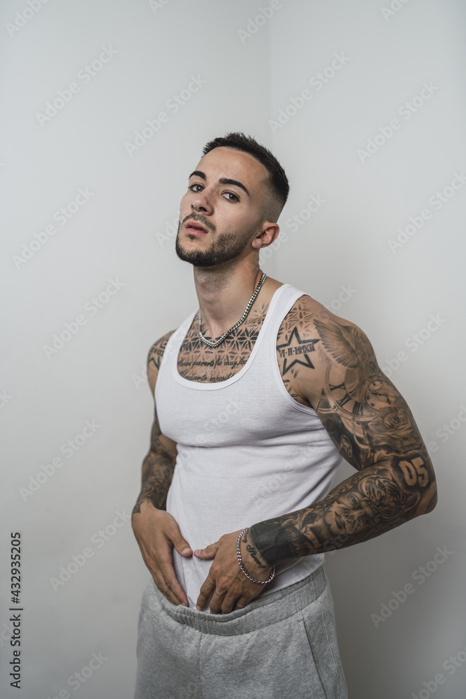 Poster Portrait of a cool sexy tattooed Spanish male posing isolated on a white background