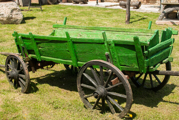 Fototapeta na wymiar Old green wooden rural cart closeup in village house garden