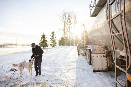 Driver Patting Dog Beside Milk Tanker Truck