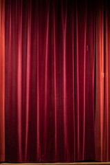 Detail, texture and fabric of theatrical red folded curtain. Artistic and dramatic shades of deep...