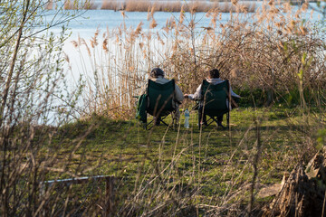 retired couple sitting by the pond