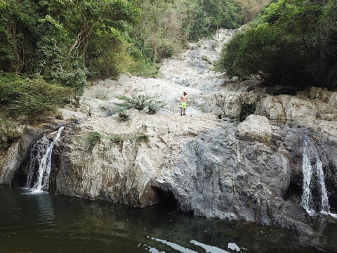 Hombre parado en una monta&ntilde;a mirando el paisaje junto a una cascada