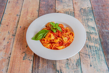 45 degree view of white plate of tortellini a la bolognese