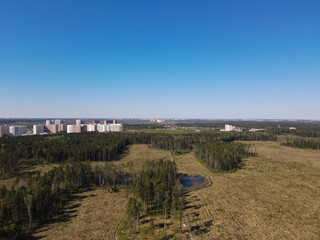 Fototapeta na wymiar View from the height of the road in the field, the forest on the outskirts of the city with residential high-rise buildings. Panoramic beautiful photo from a drone. Picturesque photo wallpaper, screen