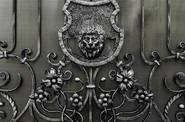 The lion's head is cast from metal and the wrought-iron elements of the gate are decorated