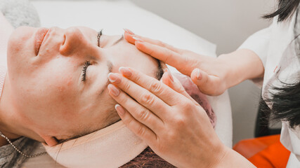 Happy and relaxed woman on cosmetology procedures, massage and applying face cream.