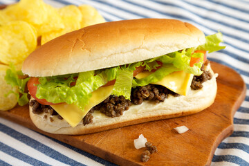 Homemade Chopped Beef Sandwich with Potato Chips on a rustic wooden board, side view.