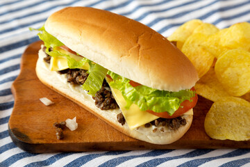 Homemade Chopped Beef Sandwich with Potato Chips on a rustic wooden board, side view.