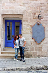 Young loving couple near the old blue door. Blue vintage doors and cafe in ancient town on background.