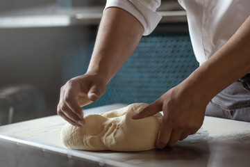 Making dough for bread by male hands in restaurant kitchen. Cooking concept.