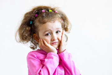closeup portrait of happy funny cute child, baby with hands near face. embarrassed attractive cheerful little girl with curls, holding her cheeks, smiling. laughing people. positive human emotions.
