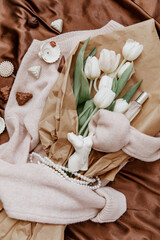 Bouquet of white tulips on a knitted sweater, top view, bouquet of  tulips for women's day, concept of spring flowers. Cozy soft background ..