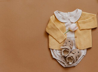 Baby clothes on brown background. Fashion baby outfit with tulips and booties. Top view, flat lay - 432947823