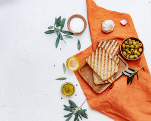 Top view olive oil, olives, toast bread and leaves on white background, space for text