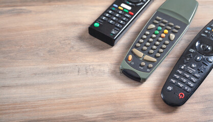 TV remote controllers on the wooden background.