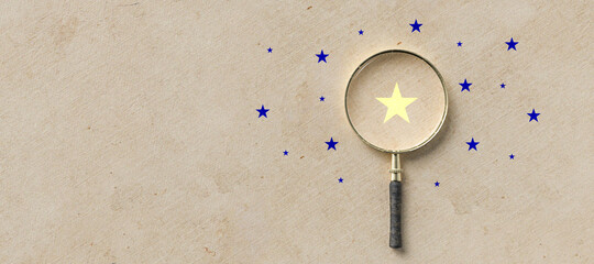 magnifying glass with a yellow star mark as symbol for finding a solution on paper background