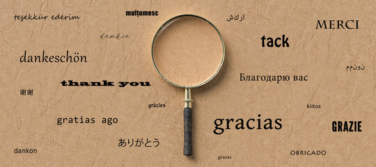 magnifying glass with the message THANK YOU in many languages on paper background