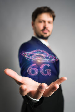 businessman presenting a hologram with message 6G on grey background