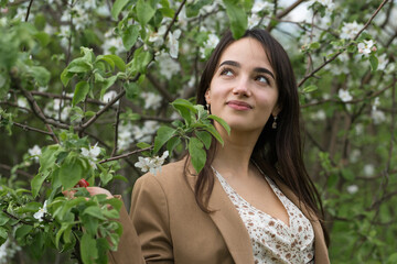 Portrait of a positive cheerful brunette girl in a green spring park.