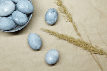 Colored blue-gray marble eggs lie randomly on the craft paper