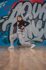 Attractive young woman doing breakdance move over graffiti background