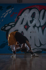 African American hip hop dancer (breakdancer) performing over graffiti background in dark silhouette exposure.