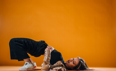Young dance artist perform acrobat moves isolated on orange background