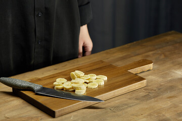 Banana sliced on a chopping board next to a kitchen knife. Healthy food concept