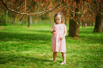 Adorable three year old girl in pink dress enjoying sunny spring day in Park of Sceaux near Paris