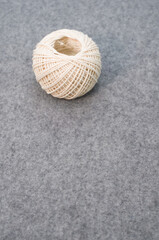 Single ball of white yarn on a woolen gray background