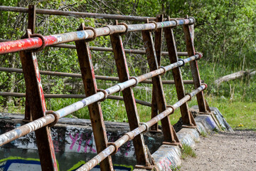 rusted and graffiti painted railing along the river