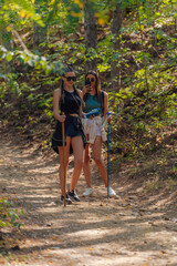 Sisters hiking through beautiful woods while wearing a backpack and enjoying nature. Female bonding.