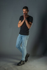 Studio photoshoot of a good-looking man posing in jeans and black shirt