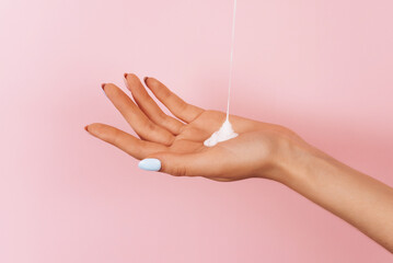 a stream of body cream pours onto a woman's hand. Skin moisturizer concept. Copy space