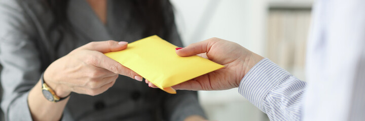Woman hands over full envelope to her interlocutor