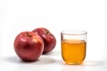 Close up of a glass of apple juice, with a whole and half apple. Natural apple juice on white background