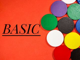 Colorful pieces of wood on red background with text BASIC. Business concept.