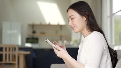 自宅でスマートフォンを使う女性 © taka